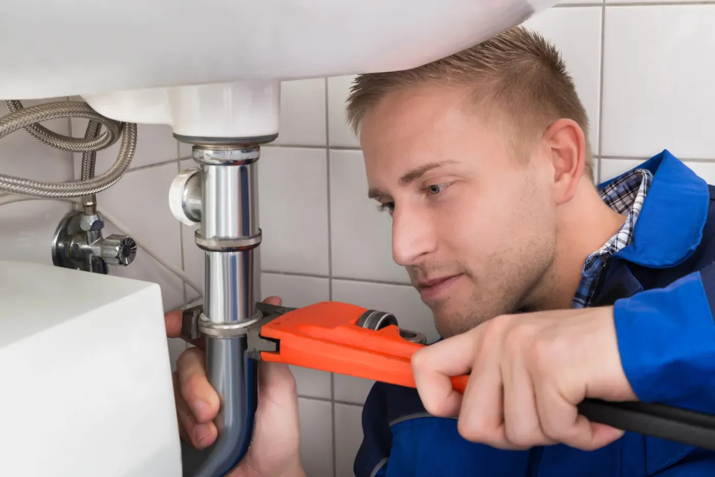 Plombier réparant le siphon d'un lavabo lors d'un dépannage à Paris 12e (75012)